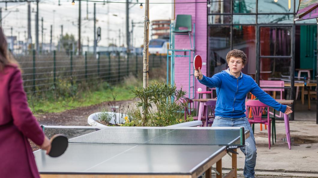 Pingpongende jongen in blauwe trui